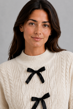 Women’s cable knit cardigan with feminine bow tie front, long sleeves and textured knitted design for autumn and winter layering.