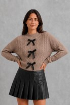 Women’s cable knit cardigan with feminine bow tie front, long sleeves and textured knitted design for autumn and winter layering.