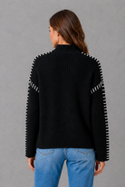 Women’s oversized black crew neck knit jumper with white contrast stitch detailing across the shoulders and long sleeves.
