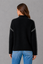 Women’s oversized black crew neck knit jumper with white contrast stitch detailing across the shoulders and long sleeves.
