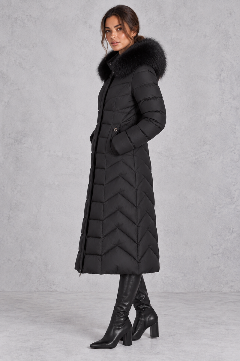 Women’s longline puffer coat with a plush faux fur-trimmed hood, chevron quilting, padded sleeves and a gently defined waist.