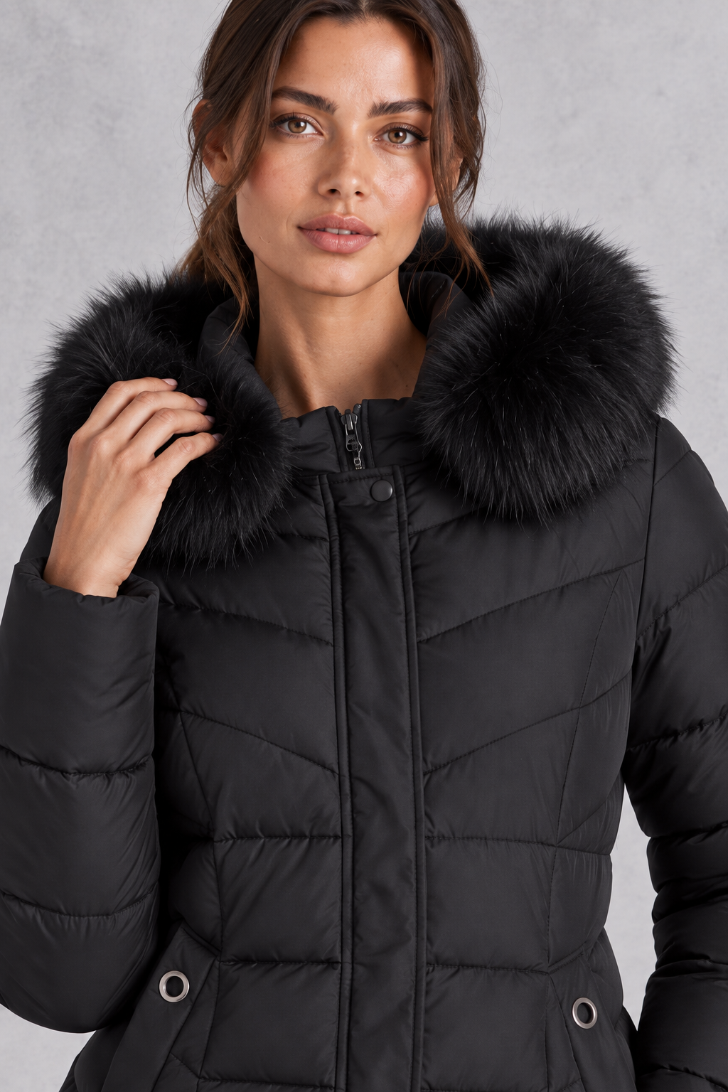 Women’s longline puffer coat with a plush faux fur-trimmed hood, chevron quilting, padded sleeves and a gently defined waist.