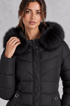 Women’s longline puffer coat with a plush faux fur-trimmed hood, chevron quilting, padded sleeves and a gently defined waist.