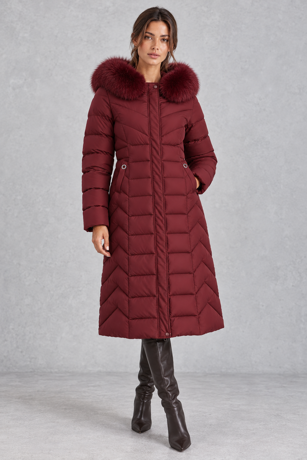 Women’s longline puffer coat with a plush faux fur-trimmed hood, chevron quilting, padded sleeves and a gently defined waist.
