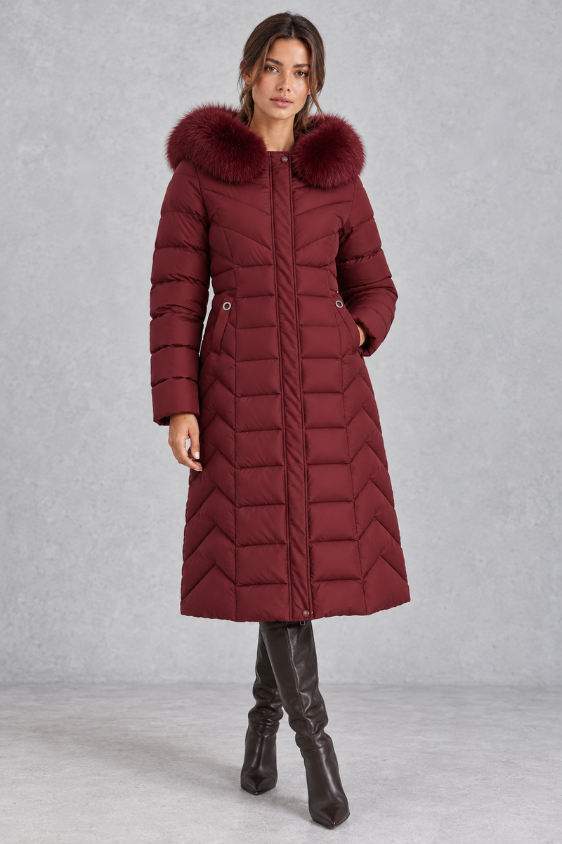 Women’s longline puffer coat with a plush faux fur-trimmed hood, chevron quilting, padded sleeves and a gently defined waist.