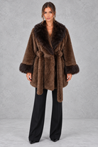Women’s belted coat with an oversized faux fur shawl collar, matching faux fur cuffs, wrap-style front and defined waist.