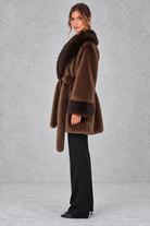 Women’s belted coat with an oversized faux fur shawl collar, matching faux fur cuffs, wrap-style front and defined waist.
