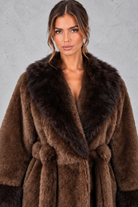 Women’s belted coat with an oversized faux fur shawl collar, matching faux fur cuffs, wrap-style front and defined waist.