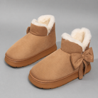 Women's faux suede winter boot slippers with plush fleece lining, side bow detail, cushioned platform sole and non-slip outsole, designed for warm, comfortable indoor wear and light outdoor use during autumn and winter.