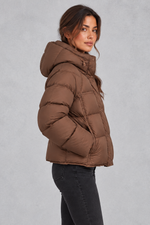 Women’s hooded puffer jacket with generous padding, a large hood, high protective neckline, long sleeves and relaxed silhouette.