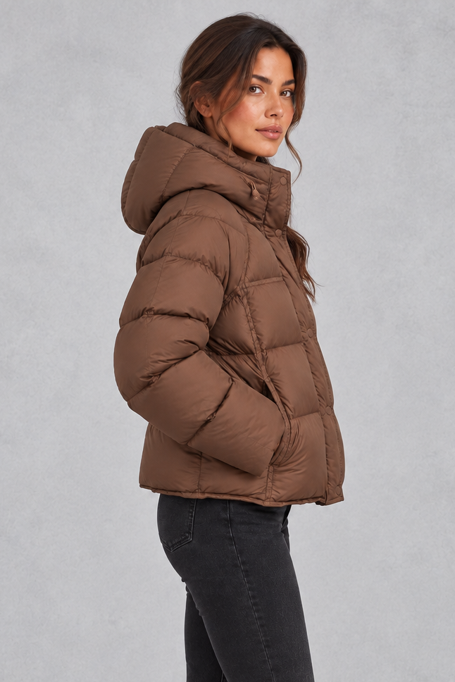 Women’s hooded puffer jacket with generous padding, a large hood, high protective neckline, long sleeves and relaxed silhouette.