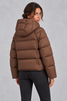 Women’s hooded puffer jacket with generous padding, a large hood, high protective neckline, long sleeves and relaxed silhouette.