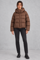 Women’s hooded puffer jacket with generous padding, a large hood, high protective neckline, long sleeves and relaxed silhouette.