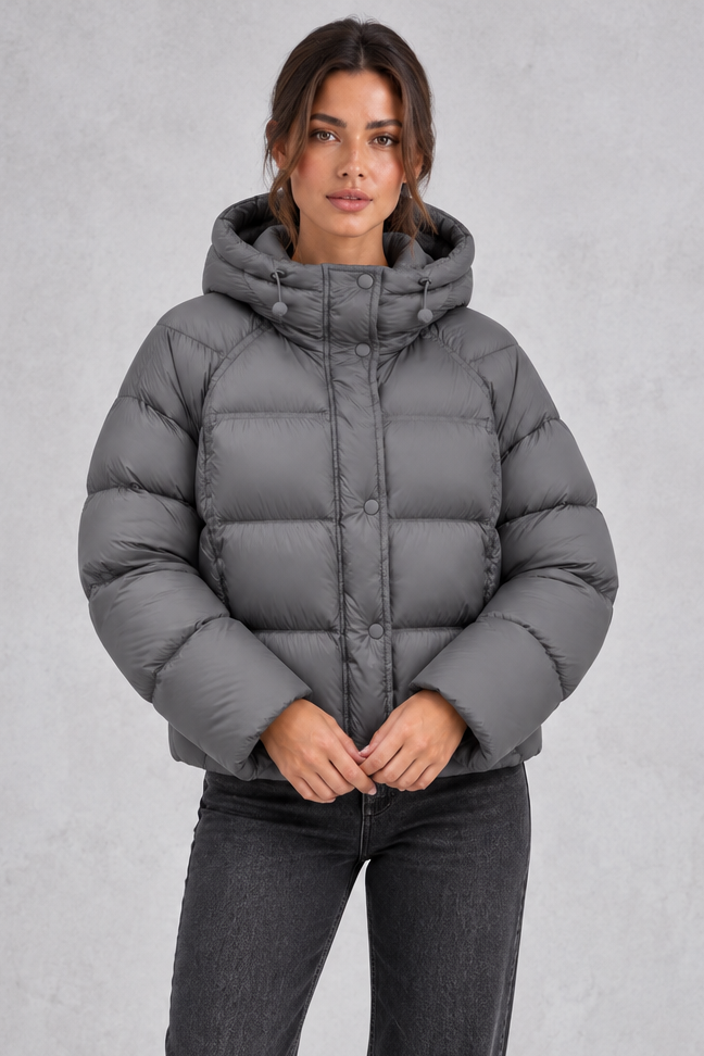 Women’s hooded puffer jacket with generous padding, a large hood, high protective neckline, long sleeves and relaxed silhouette.