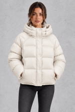 Women’s hooded puffer jacket with generous padding, a large hood, high protective neckline, long sleeves and relaxed silhouette.