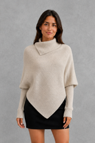 Women’s high neck knit jumper with oversized batwing sleeves, rib-knit texture and an asymmetric split hem.