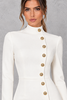 Women’s high neck mini dress with long sleeves, metallic button detailing, a statement split and sleek streamlined silhouette.
