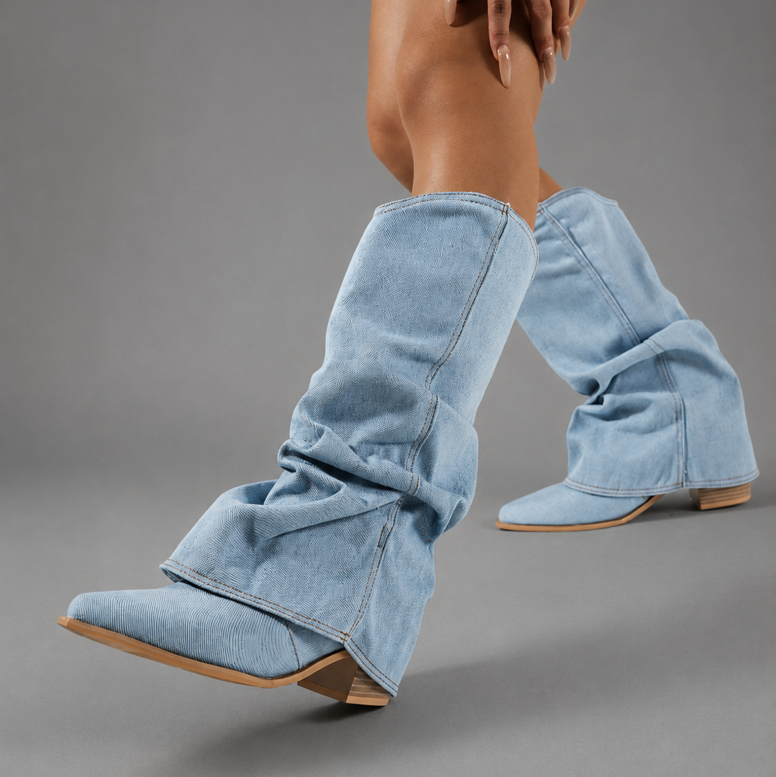 Women’s light blue denim knee-high boots with ruched shafts, pointed toes and square block heels.