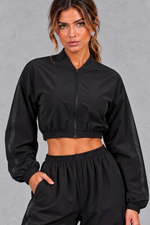 Women's black cropped zip-up sports jacket – close-up of collar, zip and elasticated hem