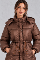 Women’s longline hooded puffer coat with quilted padding, a high neckline, adjustable drawstring waist and practical side pockets.
