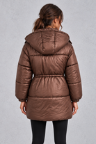 Women’s longline hooded puffer coat with quilted padding, a high neckline, adjustable drawstring waist and practical side pockets.