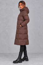 Women’s longline hooded puffer winter coat with streamlined quilting, a high neckline, full zip front and practical side pockets.