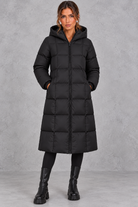 Women’s longline hooded puffer winter coat with streamlined quilting, a high neckline, full zip front and practical side pockets.