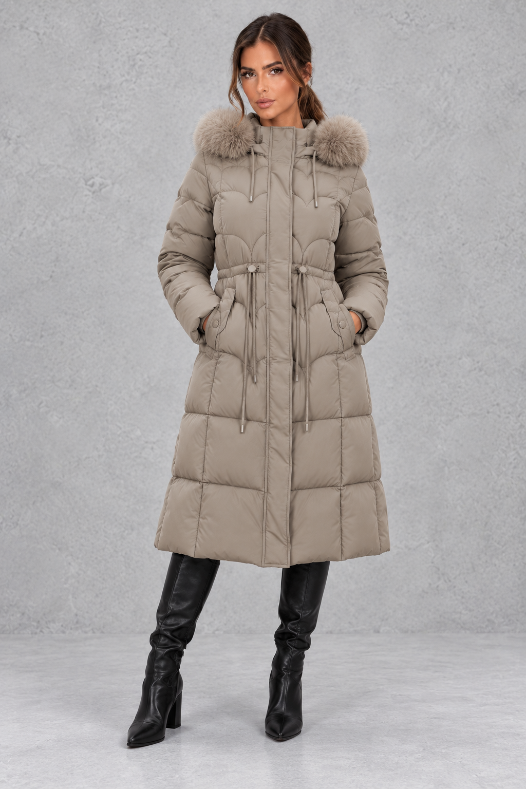 Women’s longline quilted puffer coat with a detachable faux fur hood, adjustable drawstring waist and warm padded construction.