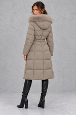 Women’s longline quilted puffer coat with a detachable faux fur hood, adjustable drawstring waist and warm padded construction.