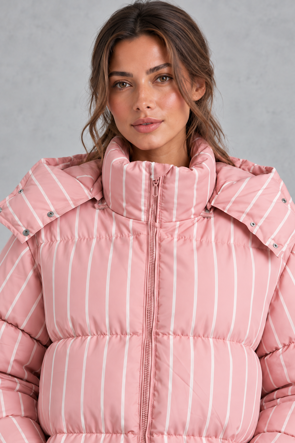 Women’s pink and white striped oversized hooded puffer jacket with horizontal quilting, a high stand collar and voluminous padded silhouette.