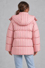 Women’s pink and white striped oversized hooded puffer jacket with horizontal quilting, a high stand collar and voluminous padded silhouette.