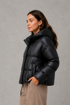 Women’s oversized hooded puffer jacket with a protective high collar, wide padded sleeves and a relaxed hip-length silhouette for winter layering.