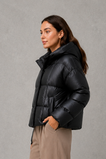 Women’s oversized hooded puffer jacket with a protective high collar, wide padded sleeves and a relaxed hip-length silhouette for winter layering.