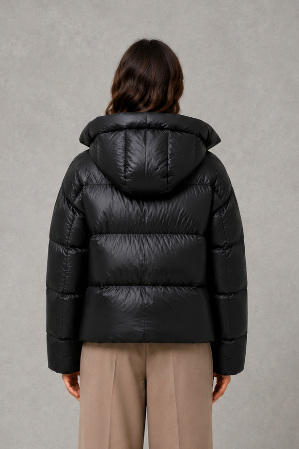 Women’s oversized hooded puffer jacket with a protective high collar, wide padded sleeves and a relaxed hip-length silhouette for winter layering.