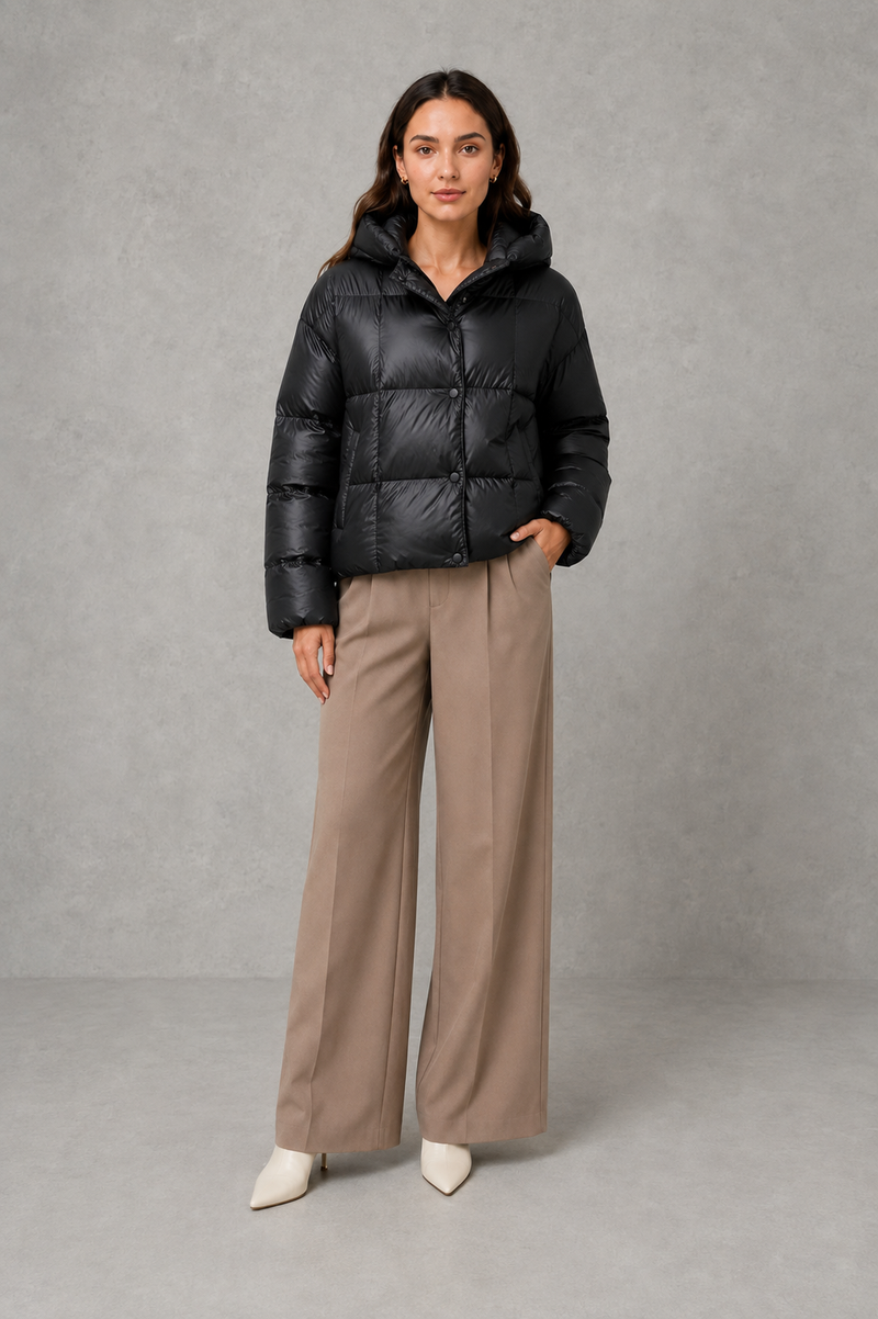 Women’s oversized hooded puffer jacket with a protective high collar, wide padded sleeves and a relaxed hip-length silhouette for winter layering.