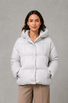 Women’s oversized hooded puffer jacket with a protective high collar, wide padded sleeves and a relaxed hip-length silhouette for winter layering.