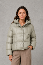 Women’s oversized hooded puffer jacket with a protective high collar, wide padded sleeves and a relaxed hip-length silhouette for winter layering.