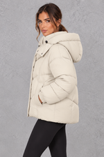 Women’s cream oversized hooded puffer jacket with geometric quilting, generous padding, a high collar and adjustable drawcord hem.