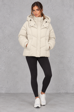 Women’s cream oversized hooded puffer jacket with geometric quilting, generous padding, a high collar and adjustable drawcord hem.