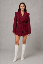 Women’s pinstripe longline blazer with structured shoulders, lapel collar and adjustable tie waist belt.