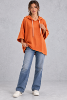 Women's plus size orange waffle knit oversized hooded jumper styled with jeans – full-length front view