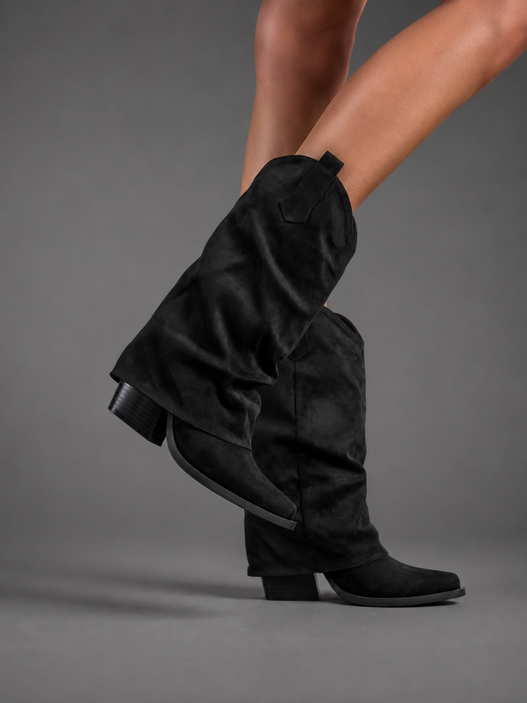 Women’s pointed toe knee high boots with a low chunky heel and relaxed Western-inspired shaft in a neutral shade.