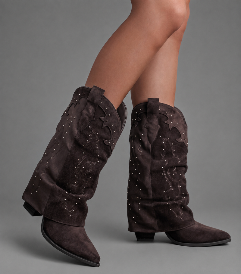 Women’s pointed toe knee high boots with a low chunky heel and relaxed Western-inspired shaft in a neutral shade.