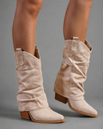 Women’s pointed toe knee high boots with a low chunky heel and relaxed Western-inspired shaft in a neutral shade.
