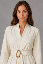 Women’s soft apricot textured floral wrap top with V-neckline, flowing bell sleeves, pleated waist and gold-tone buckle belt.