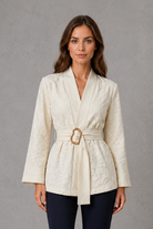 Women’s soft apricot textured floral wrap top with V-neckline, flowing bell sleeves, pleated waist and gold-tone buckle belt.