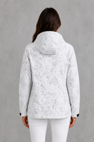Women’s waterproof leaf print jacket with a protective hood, adjustable drawstring waist and lightweight design for rainy and changeable weather.