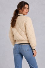 Women’s quilted bomber jacket with wave-stitch detailing, a high ribbed collar, full zip front, extended cuffs and contrast trims.