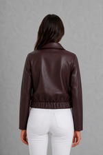 Women’s wine leather-look jacket with a tailored silhouette and front zip fastening, styled as an elegant biker-inspired autumn jacket.