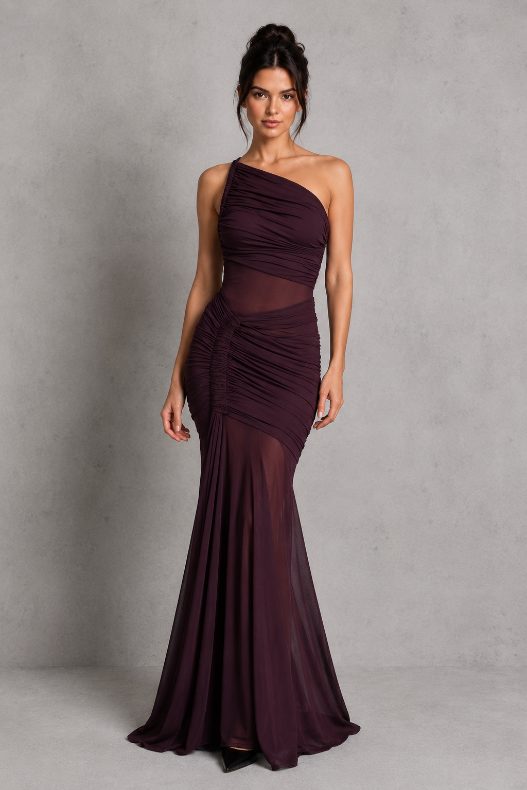 Woman wearing a one-shoulder burgundy evening gown against a gray background